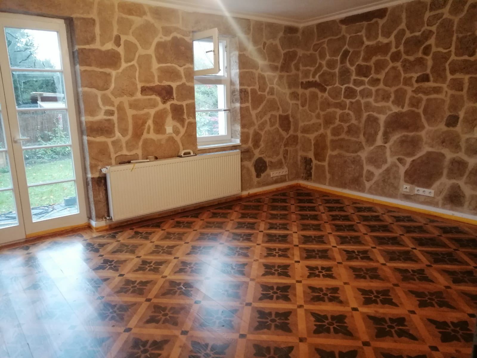 Holzdielen mit gemaltem Ornamentmuster, dahinter Wände in Bruchsteinoptik